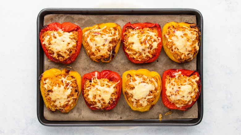 Cheesy stuffed bell peppers on parchment-lined baking sheet