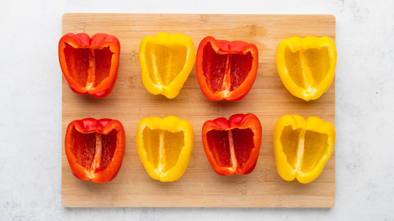 Halved bell peppers on wooden cutting board