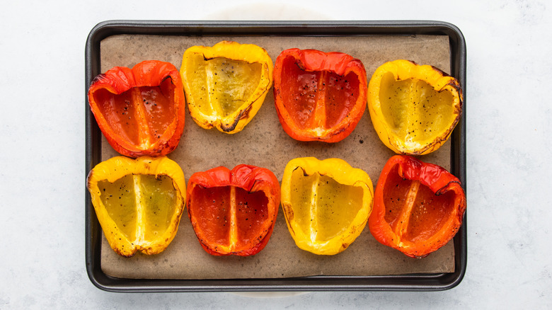 Halved bell peppers on parchment-lined baking sheet