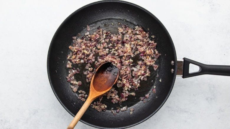 Diced red onion and garlic sauteing in frying pan