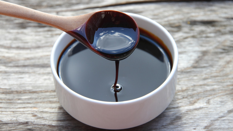 Wooden spoon drizzling molasses into a bowl