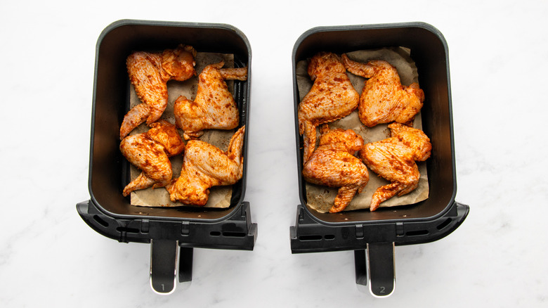 Spice-coated chicken wings in two air fryer baskets