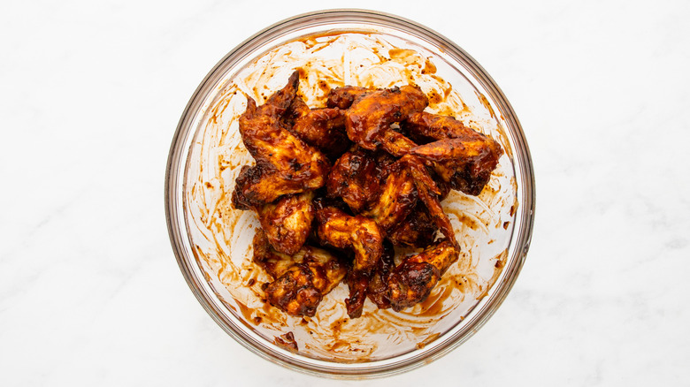 Barbecue sauce-coated chicken wings in mixing bowl