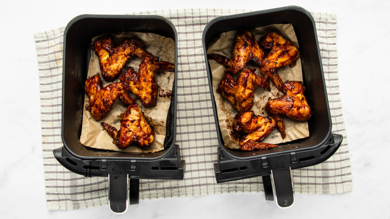 Barbecue sauce-coated chicken wings in two air fryer baskets