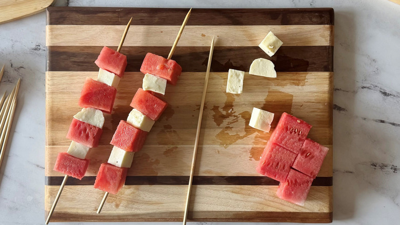 Assembling watermelon and halloumi skewers on wooden board