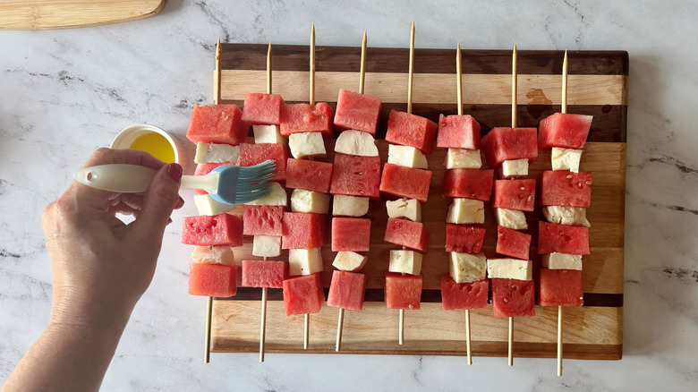 Brushing oil onto watermelon and halloumi skewers