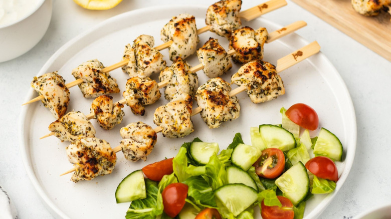 Chicken skewers on plate with side salad