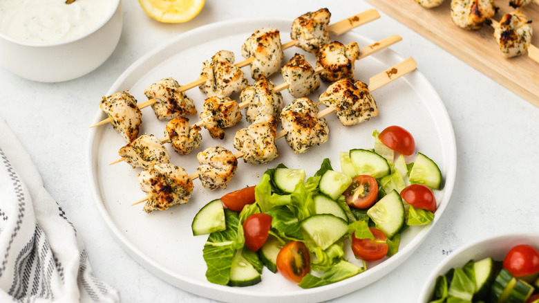 Lemon herb chicken skewers on plate with side salad