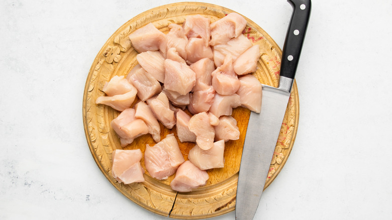 Diced chicken on wooden cutting board with knife