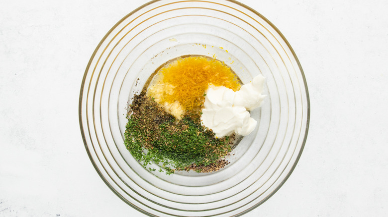 Lemon-herb marinade ingredients in glass mixing bowl