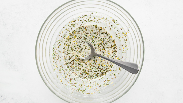 Lemon-herb marinade mixture on mixing bowl with spoon