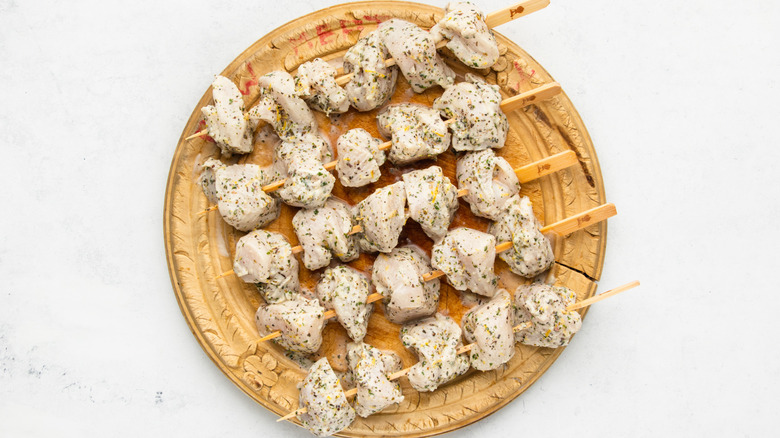 Marinated chicken breast pieces on wooden skewers