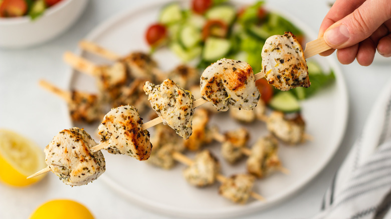 Hand holding lemon-herb chicken skewer