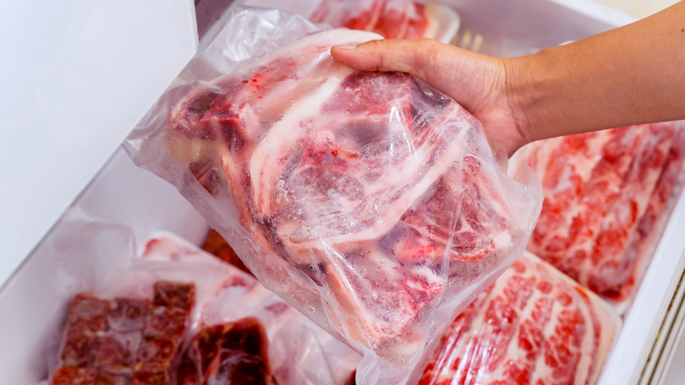 Hand holding frozen red meat in plastic
