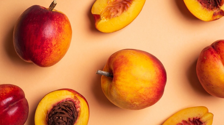Whole and halved peaches on orange backdrop
