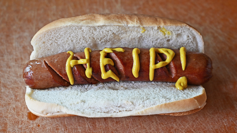 A hot dog with "help" written in mustard