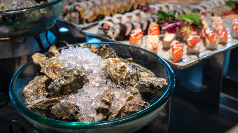 Bowl of oysters on ice next to sushi platter