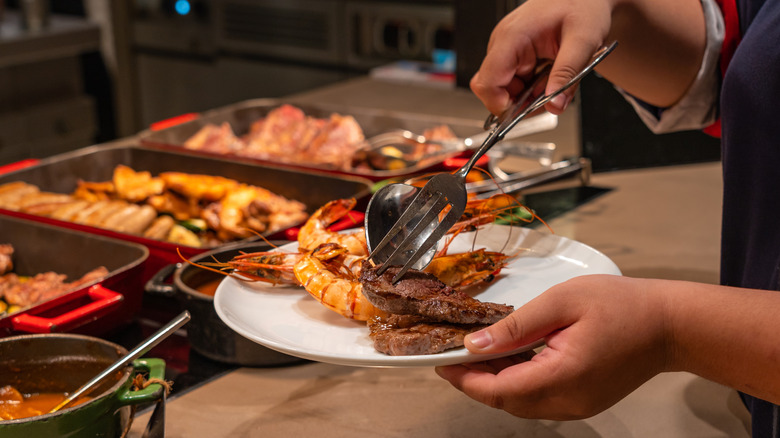 Person selecting seafood from a buffet