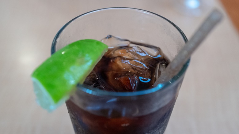 Close-up of a glass of soda with lime on rim and a straw