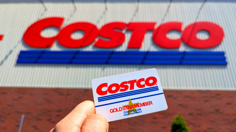 Hand holding Costco membership card outside Costco store