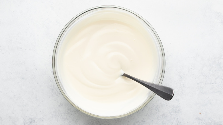 Greek yogurt in glass mixing bowl with spoon