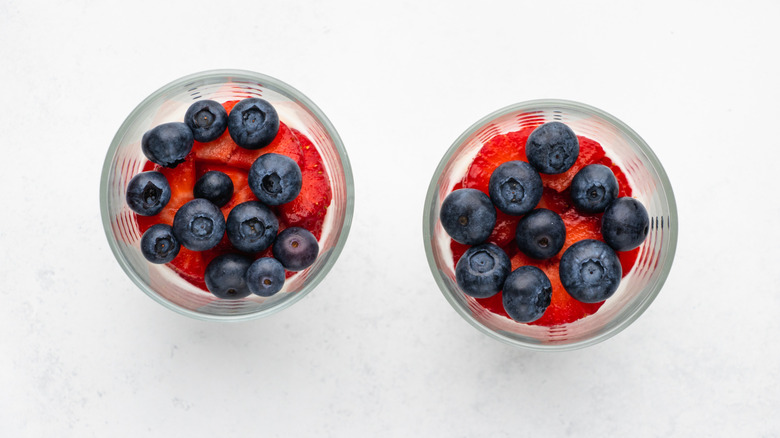 Top down view of two glasses containing sliced strawberries and blueberries