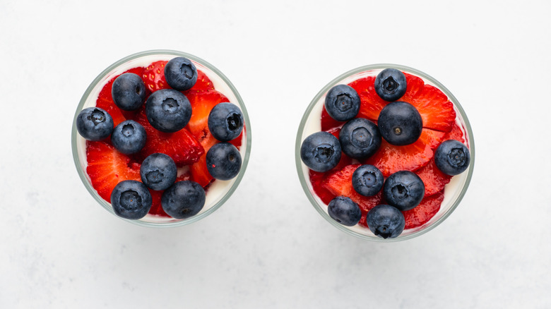 Top down view of two glasses containing sliced strawberries and blueberries