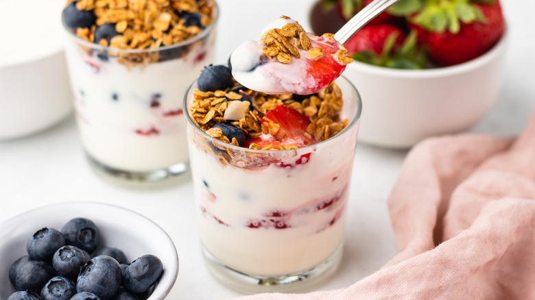 Spooning berry breakfast parfait out of serving glass