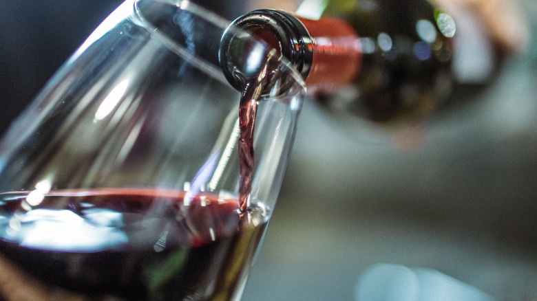 Bottle of red wine pouring into glass.