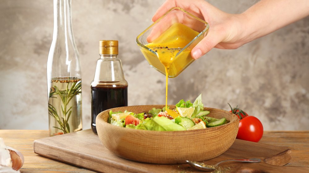 person pouring dressing over a salad
