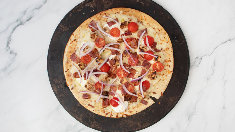 Pizza with red onion, tomato, bacon, and chicken toppings