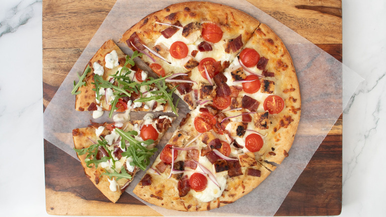 Sliced chicken bacon ranch pizza with arugula on two slices