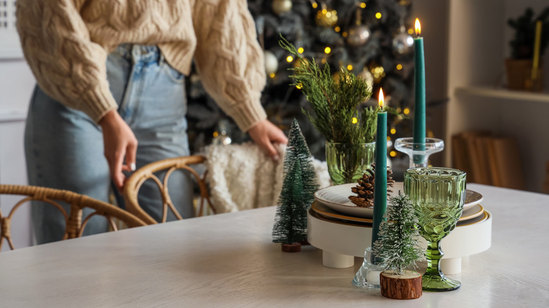 Person standing next to holiday decor on dining table