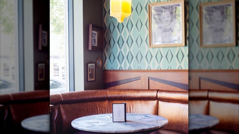 Perly's corner booth featuring green patterned wallpaper and vintage artwork