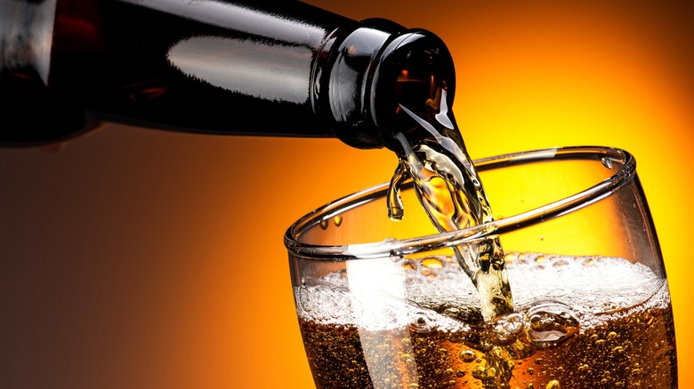 A close-up shot of a bottle of beer being poured into a glass.