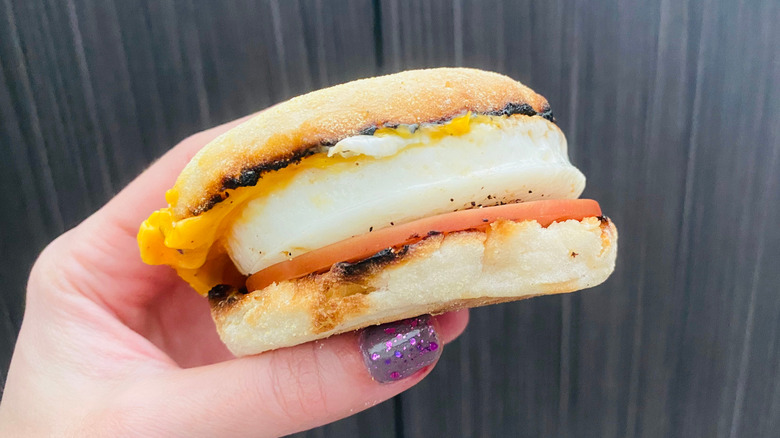 A breakfast sandwich on English muffin with egg, cheese, ham