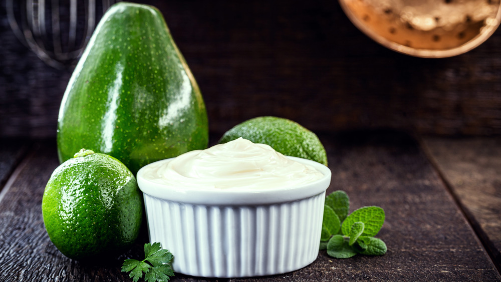 A dish of mayonnaise in front of an avocado