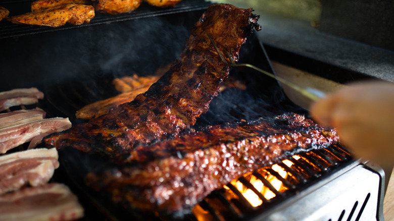 person lifting bbq ribs on grill