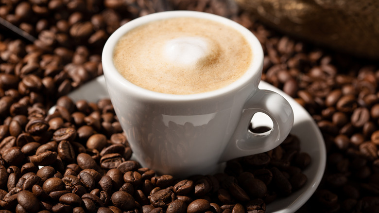 Cup of coffee amid coffee beans