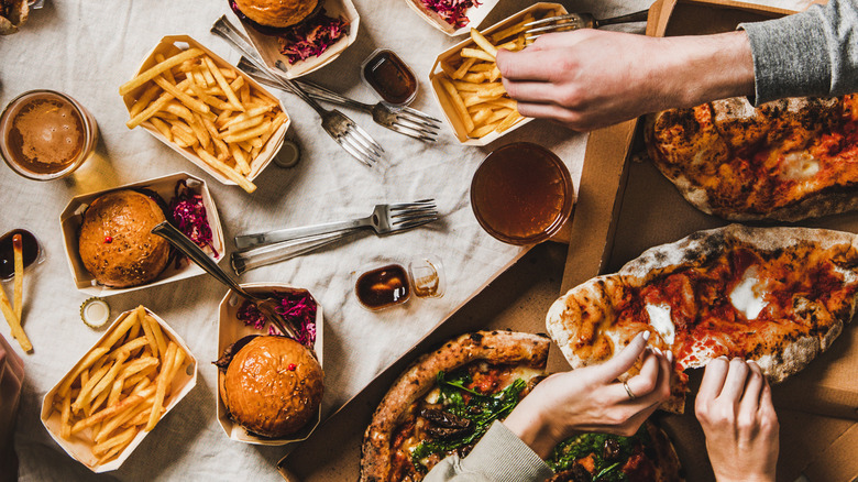 Hands reaching for an array of foods