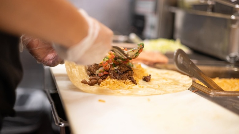 Employee filling burrito at Anna's Taqueria.