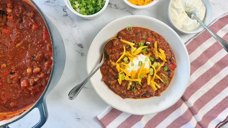 Chili in pot and serving in bowl with toppings