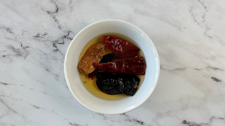 Dried chiles soaking in liquid in bowl