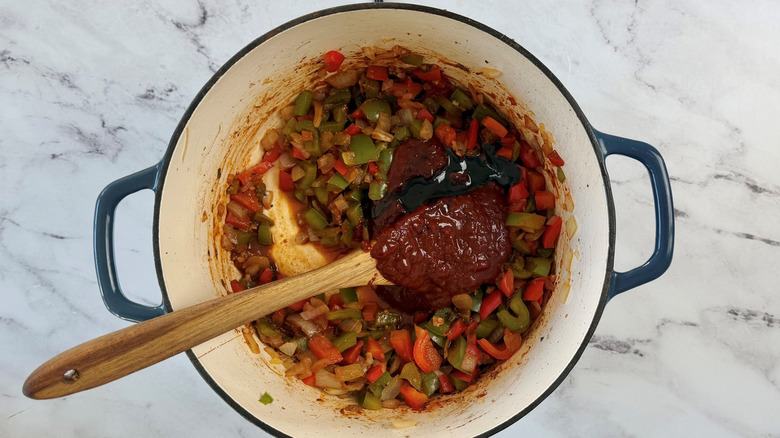 Sauteed veggies, molasses, and chile paste in pot with wooden spoon