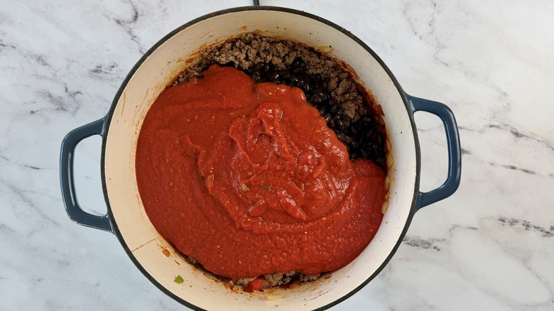 Crushed tomatoes in pot with other chili ingredients