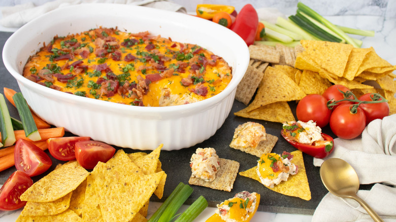 Pimento chicken bacon ranch dip in casserole dish next to dip on crackers and chips
