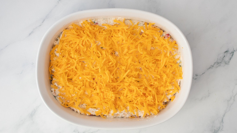 Dip topped with shredded cheddar in casserole dish