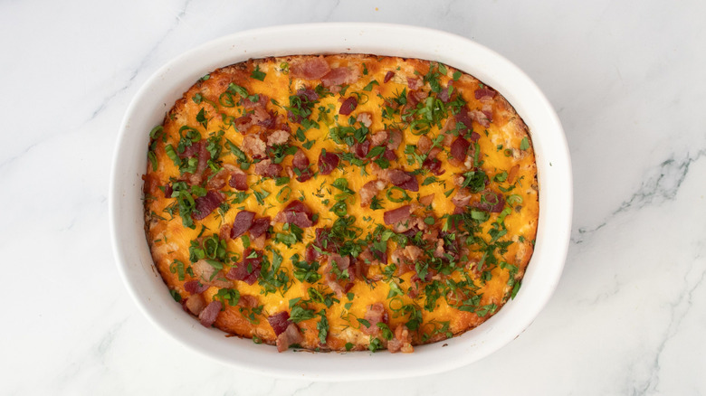 Dip garnished with bacon and herbs in casserole dish