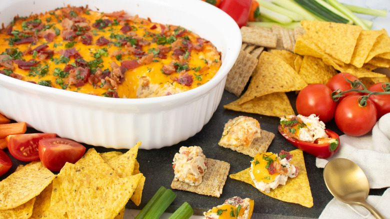 Pimento chicken bacon ranch dip in casserole dish next to assorted chips and crackers