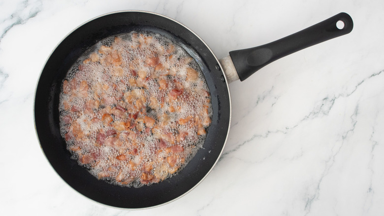 Chopped bacon cooking in pan
